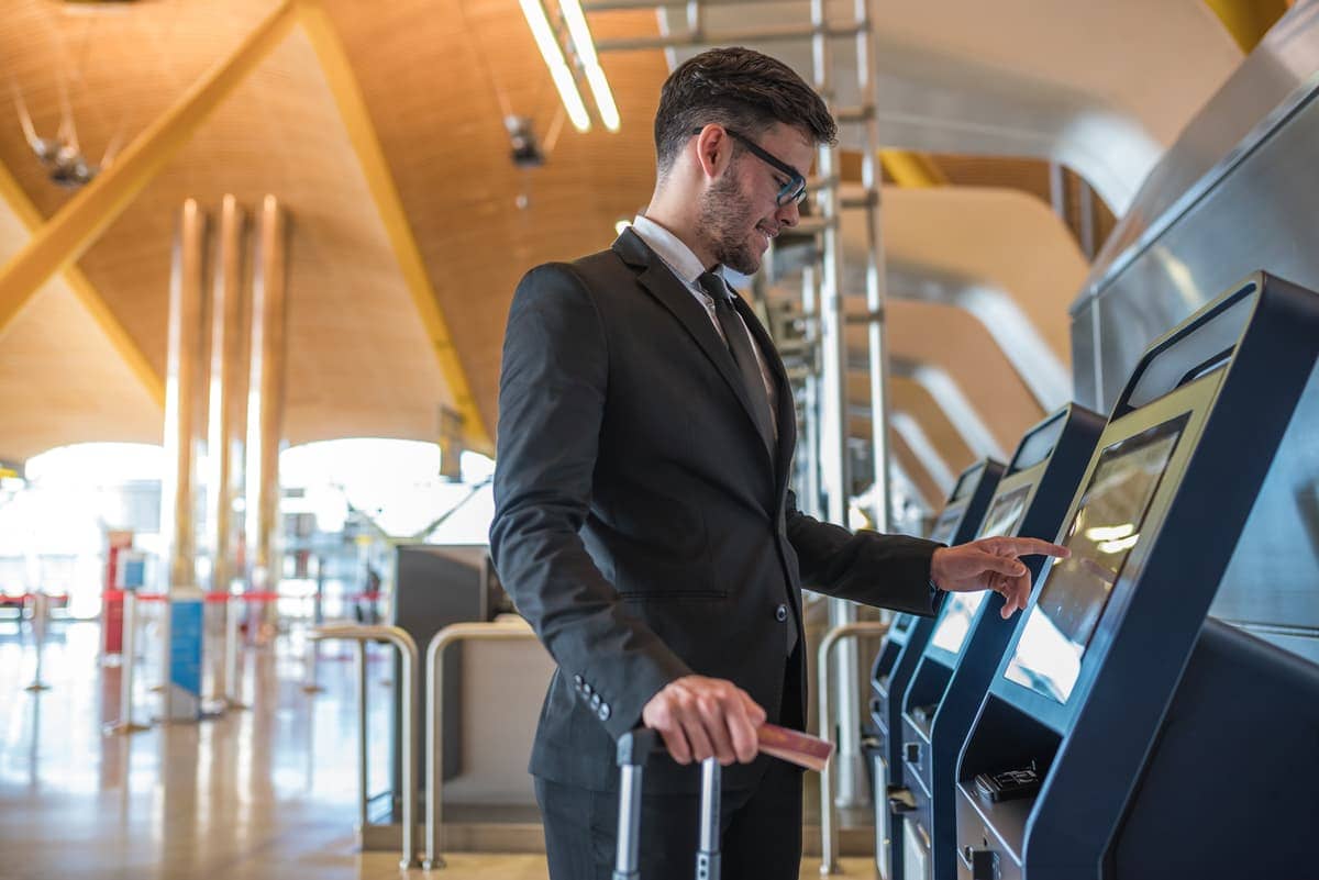 A businessman using an airport kiosk to buy foreign currency online