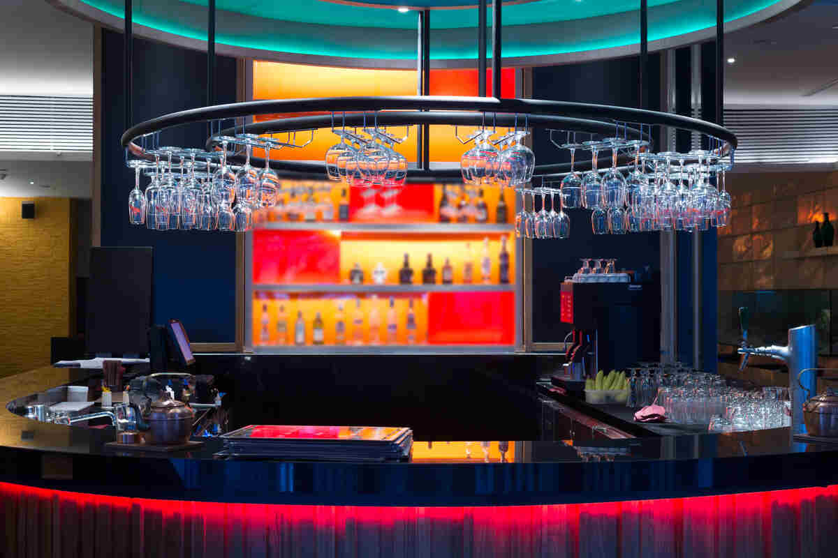 Modern bar counter with glasses and bottles lit by warm lights