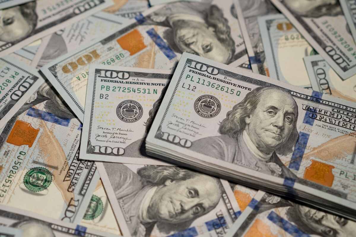 Stack of U.S. $100 bills scattered beneath, symbolizing wealth and abundance.