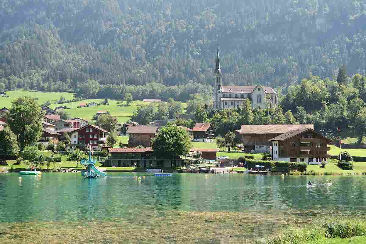 Summer in Switzerland: lake, mountains, swimming, and houses surrounded by nature.