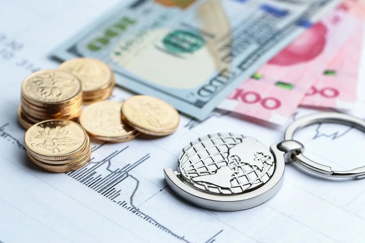 Gold coins, paper currency, and a globe on a document with financial charts