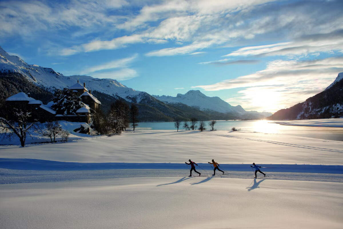 Winter in Switzerland: skiers, snow-covered mountains, and a lake in a serene winter setting.