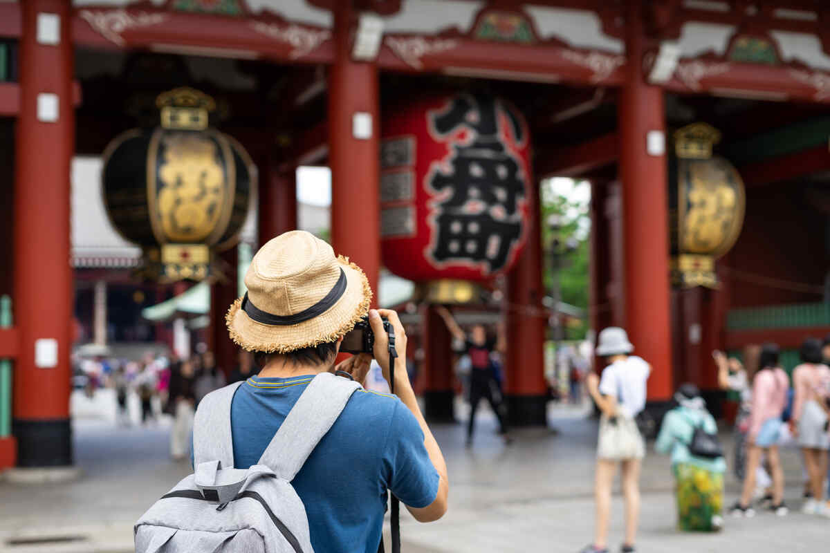 A young tourist, facing away, photographs Tokyo with skyscrapers in the background